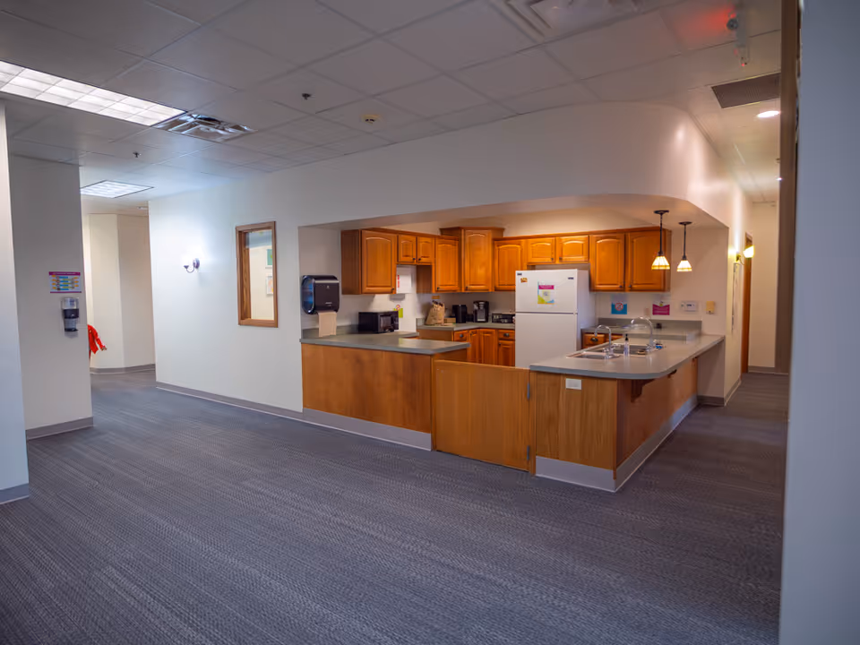 Interior view of a senior living facility kitchen with island and wooden cabinets