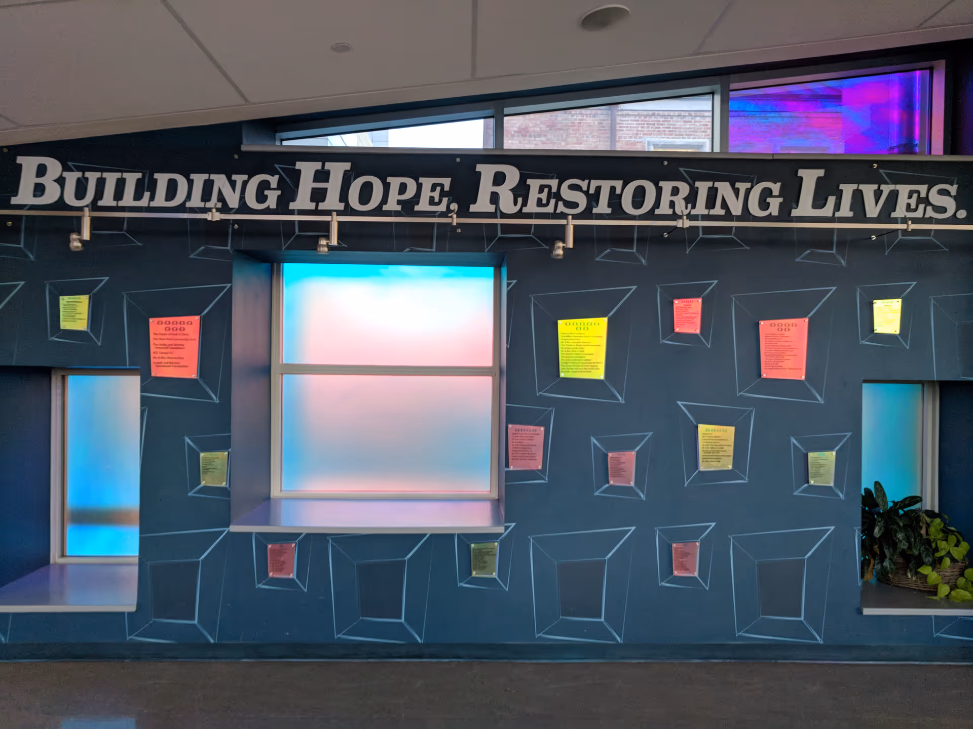 Interior wall with a large sign reading Building Hope, Restoring Lives and geometric patterns.