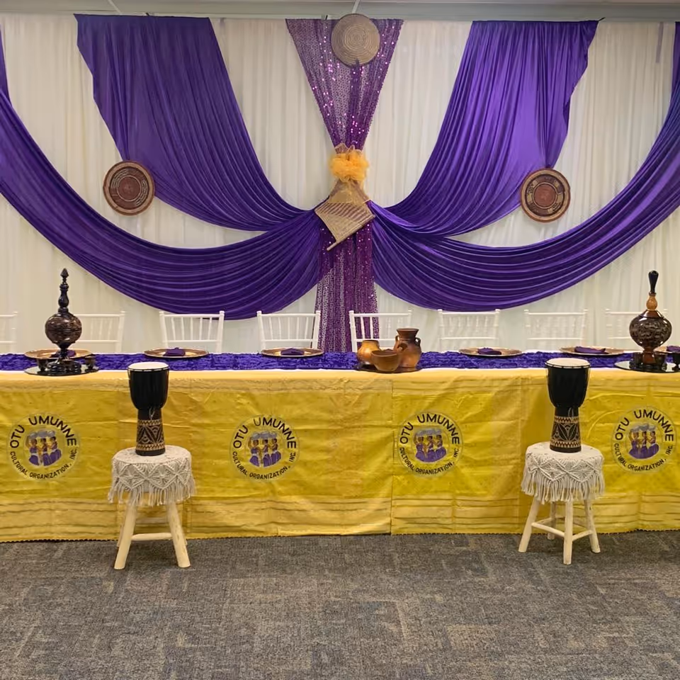 Decorated banquet table with purple and yellow drapes in an indoor dining hall.