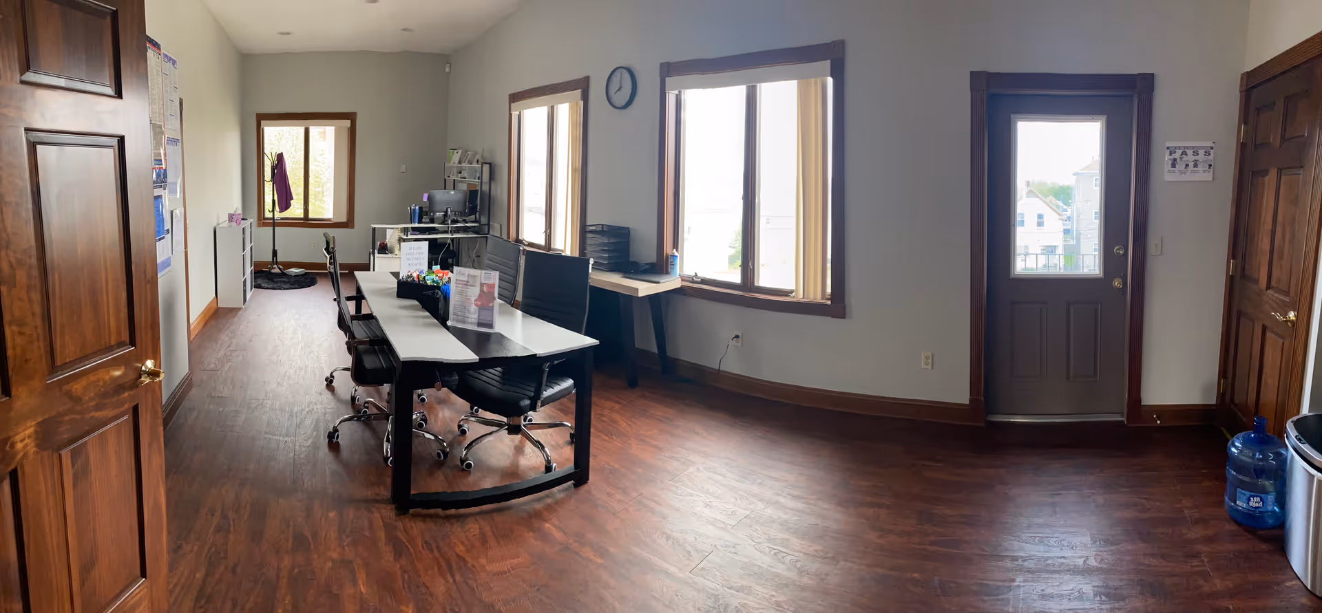 A long conference table with chairs in a bright office space near windows.