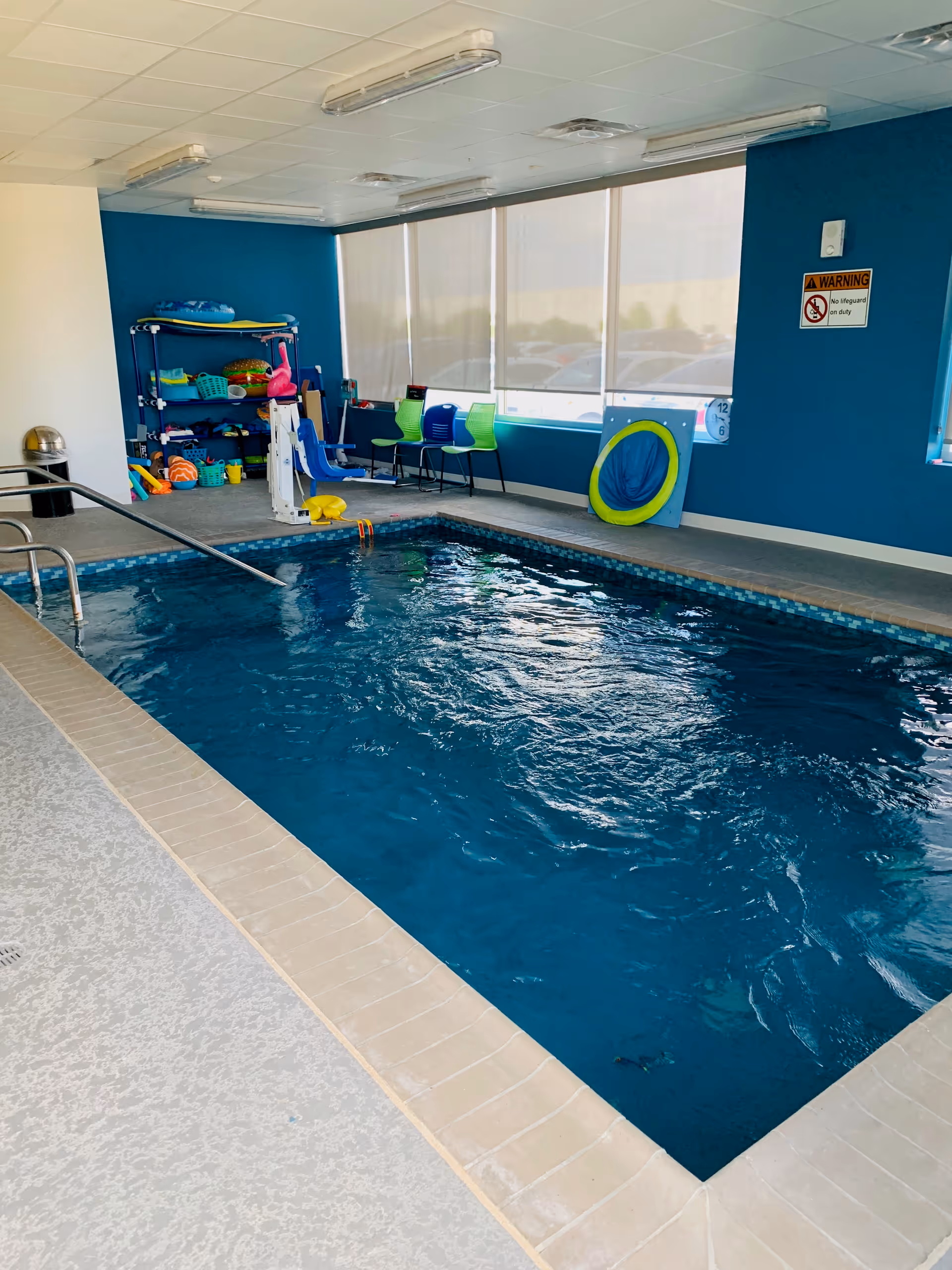 Indoor pool area with blue walls, large windows, and poolside toys.