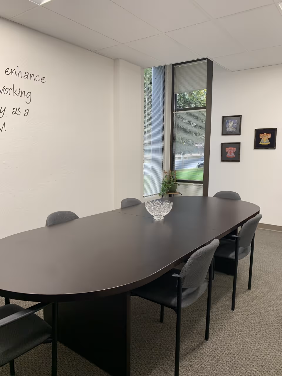 An oval conference table with chairs in a bright, windowed meeting room.