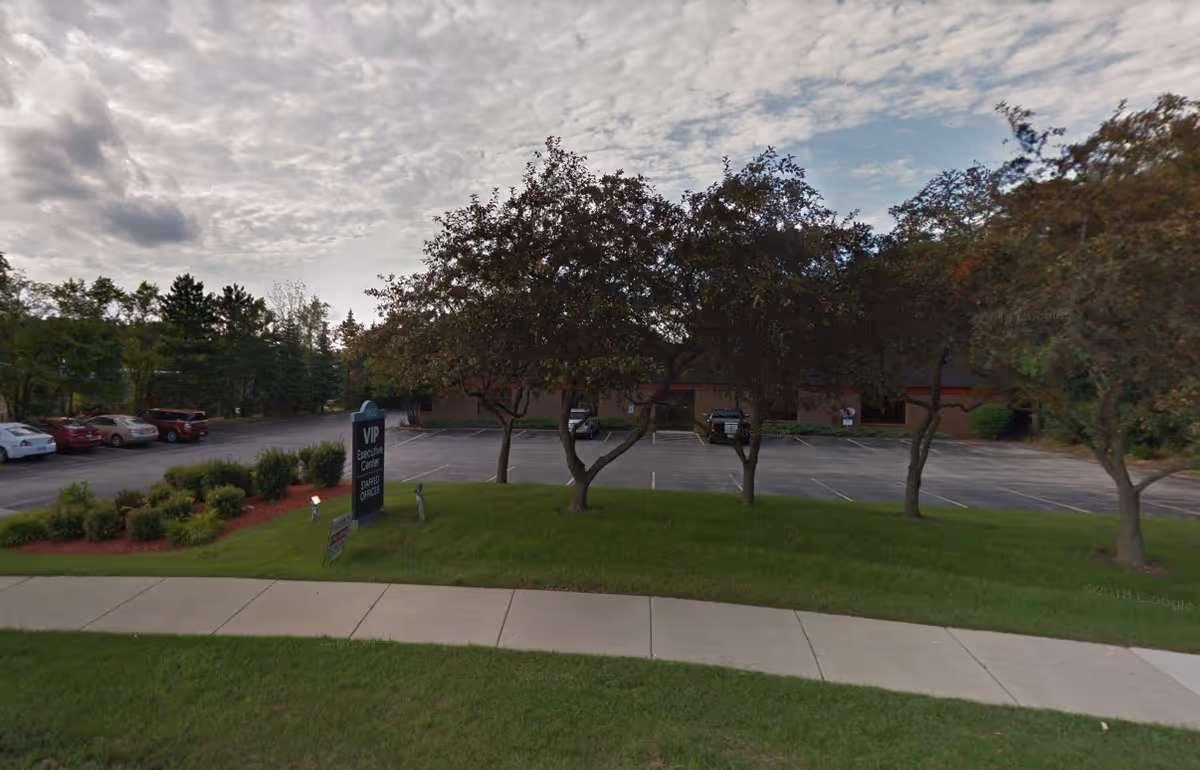 Exterior view of SYNERGY HomeCare building with parking lot and trees.