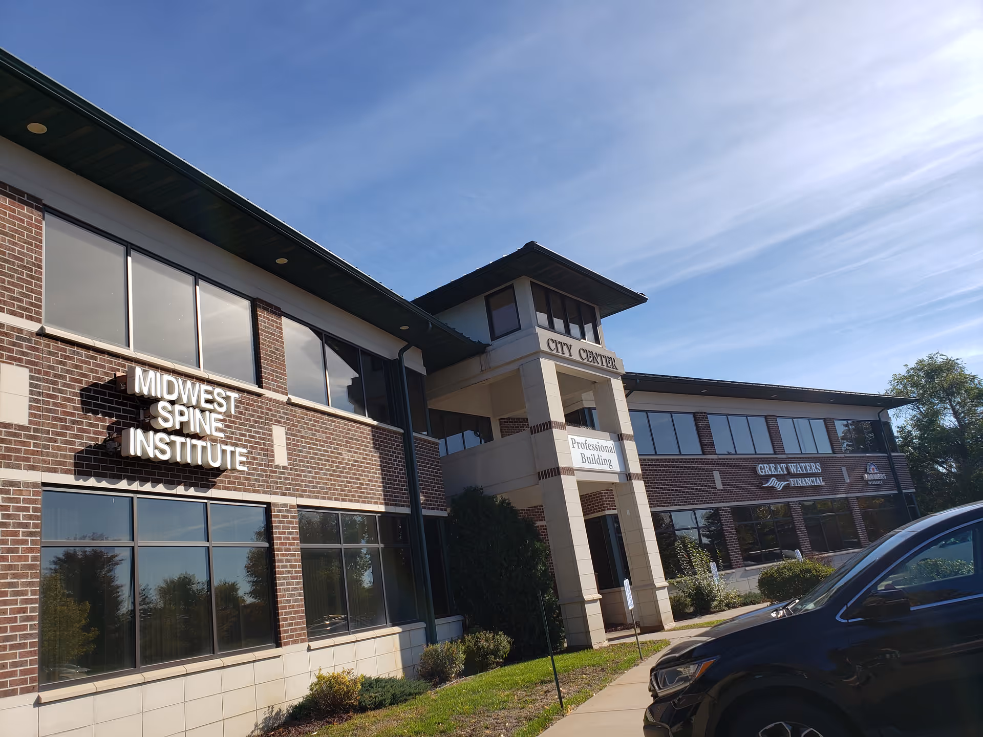 Exterior view of a brick medical complex with signs and blue sky.