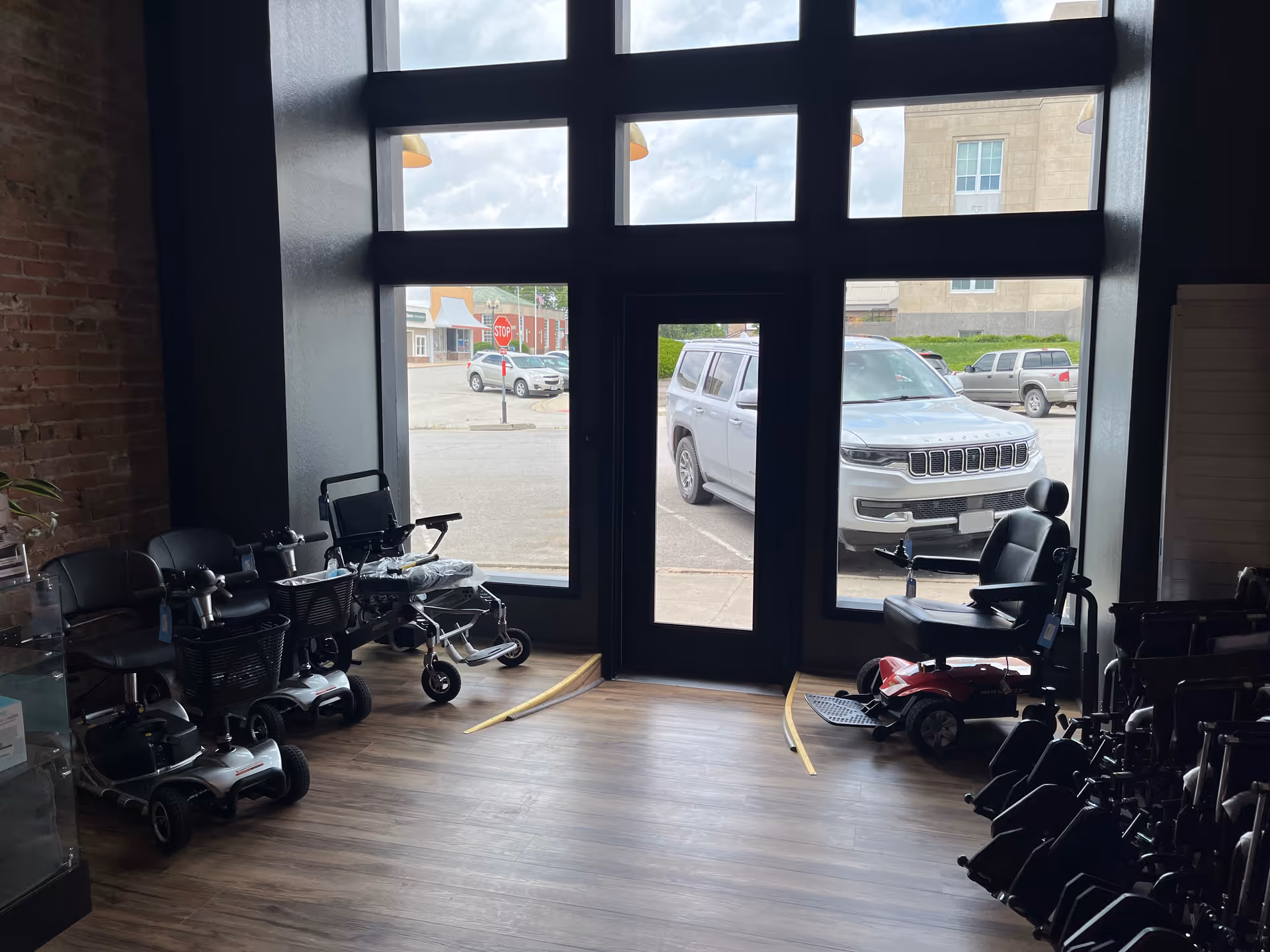 Indoor showroom with mobility scooters and wheelchairs lined up near a large glass door