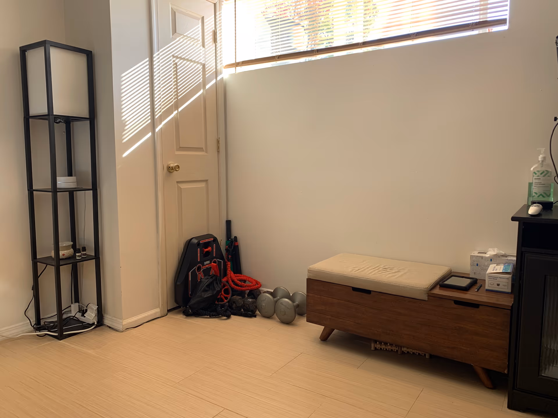 Sunlight streams through a high window onto an interior therapy room with equipment.