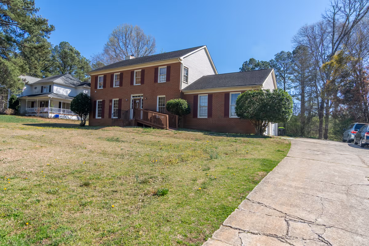 Brick two-story facility with front steps, driveway, and surrounding lawn
