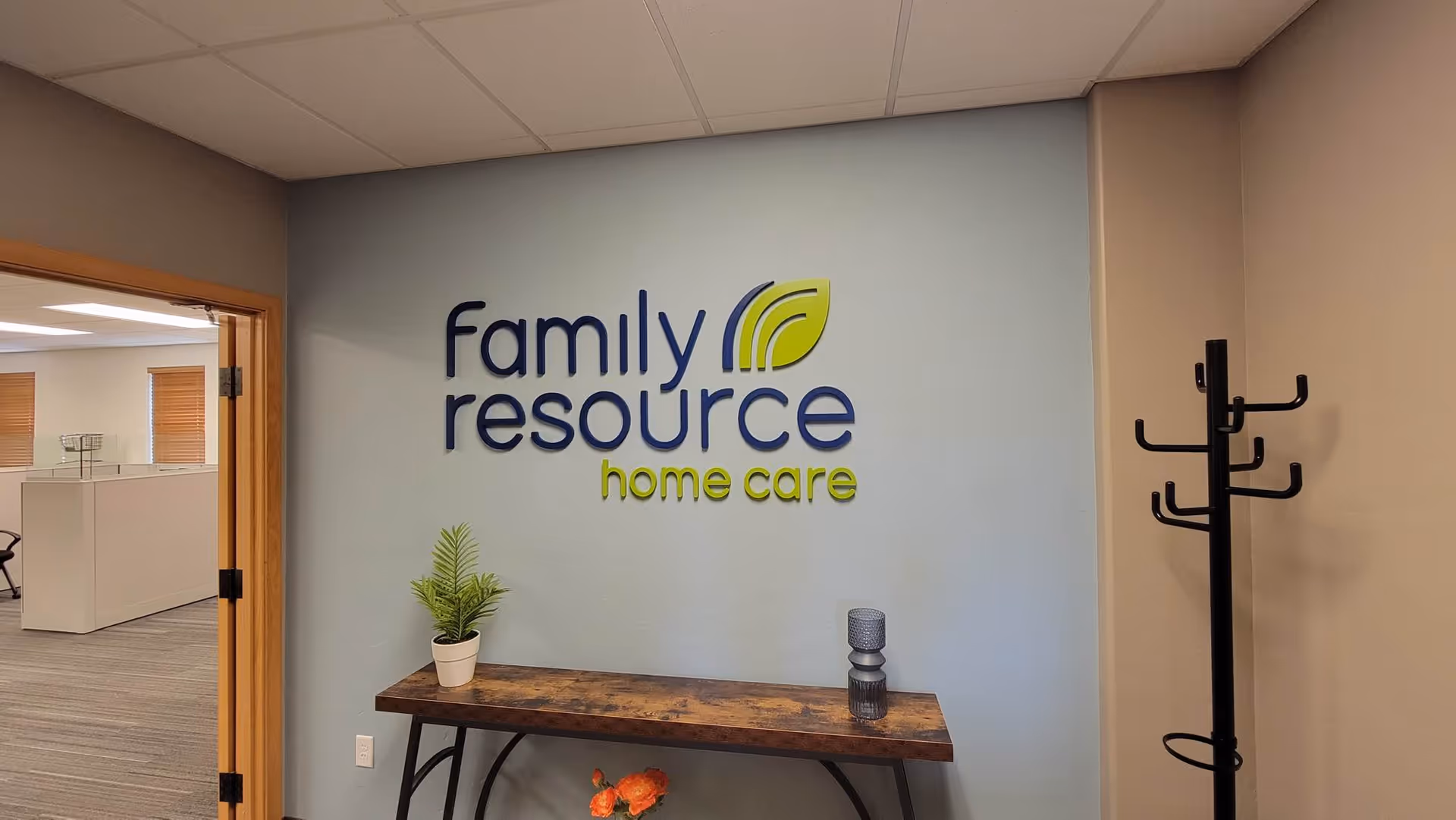 Interior wall features Family Resource Home Care logo above a wooden console table.
