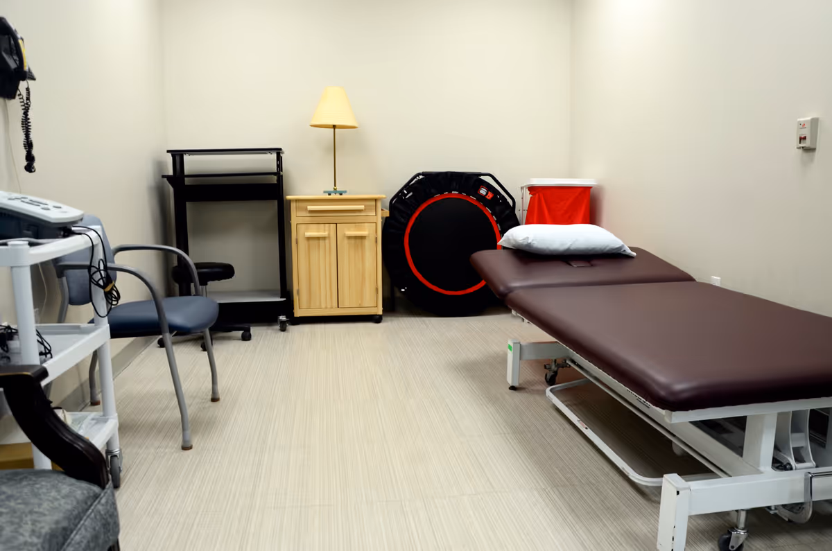 A clinical treatment room with an exam table and medical equipment.