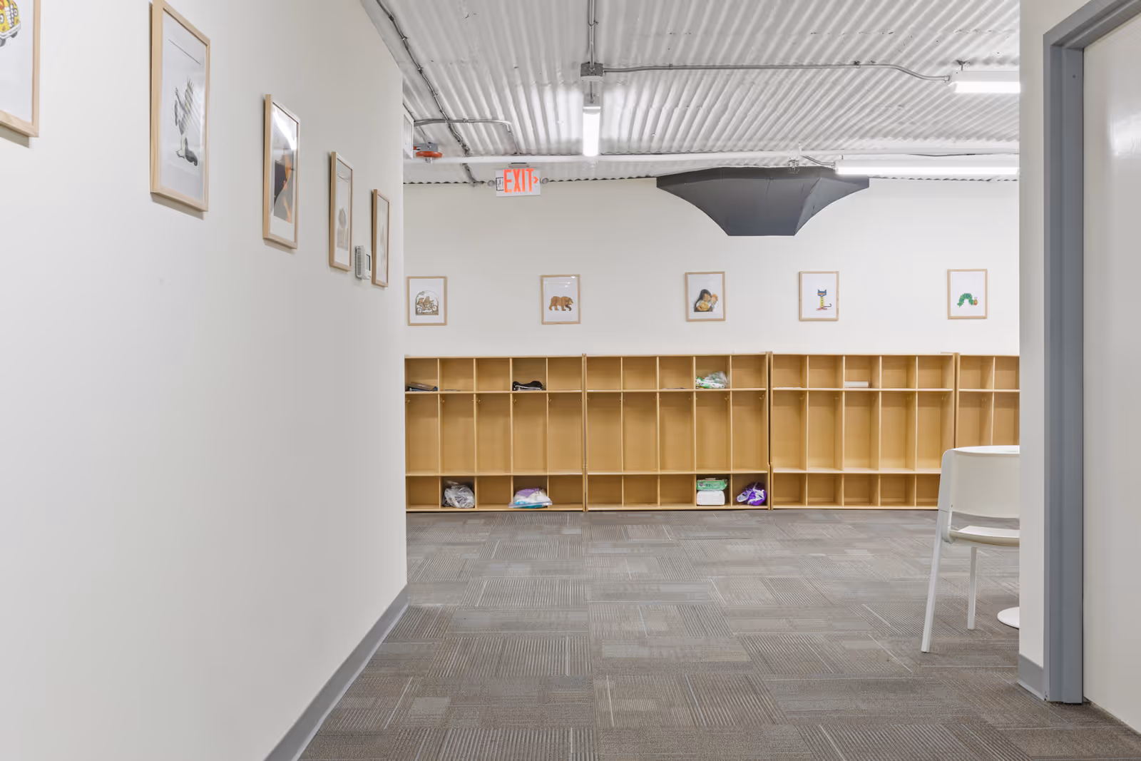 Interior hallway with row of wooden cubbies along back wall and framed art.