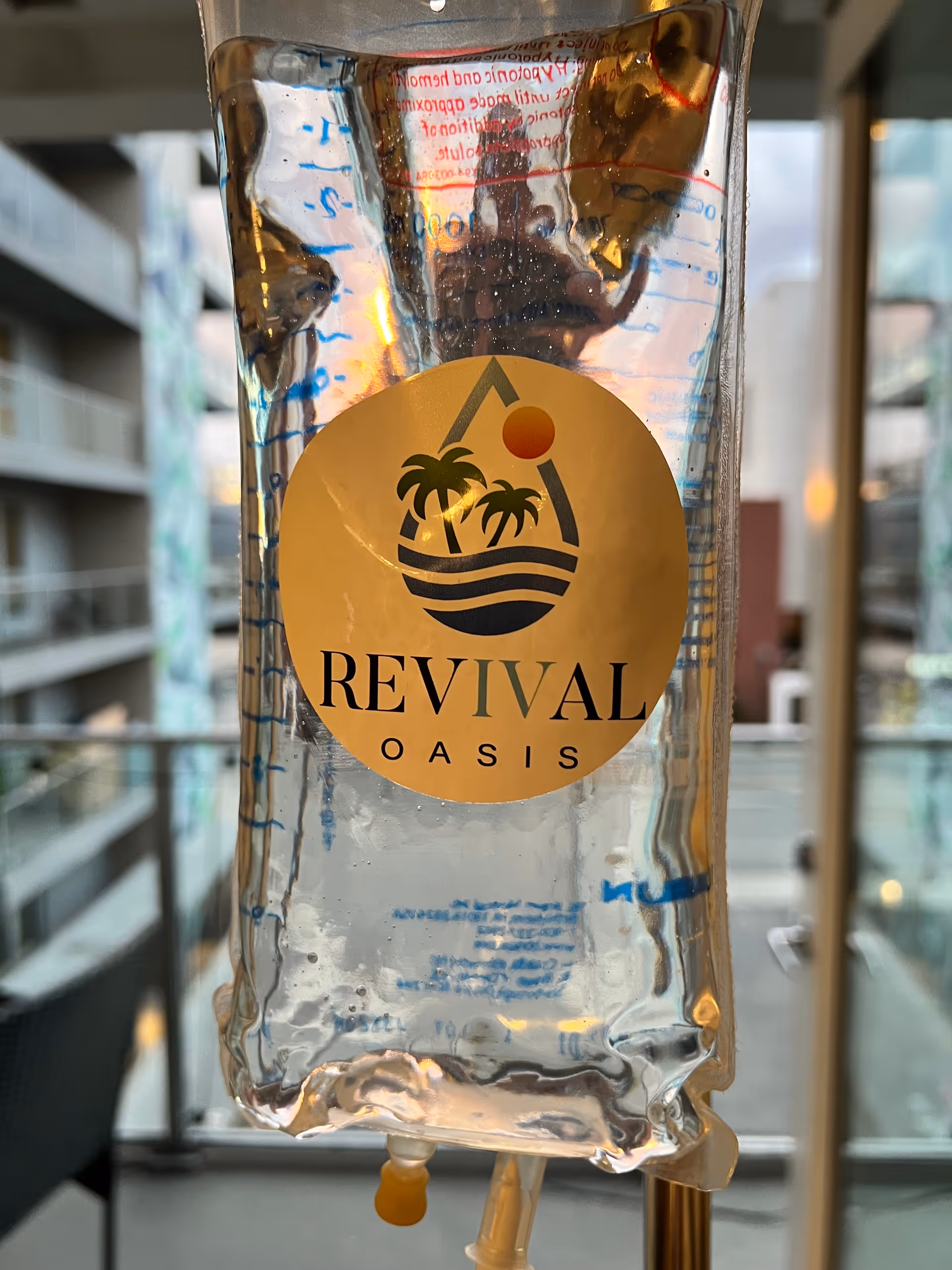 Close-up IV bag with Revival Oasis branding inside a modern indoor setting.