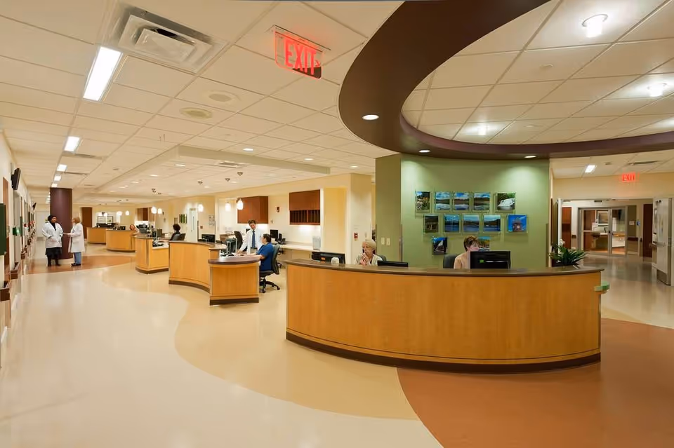 Spacious Middlesex Hospital lobby with curved wooden reception desk and staff at computers.