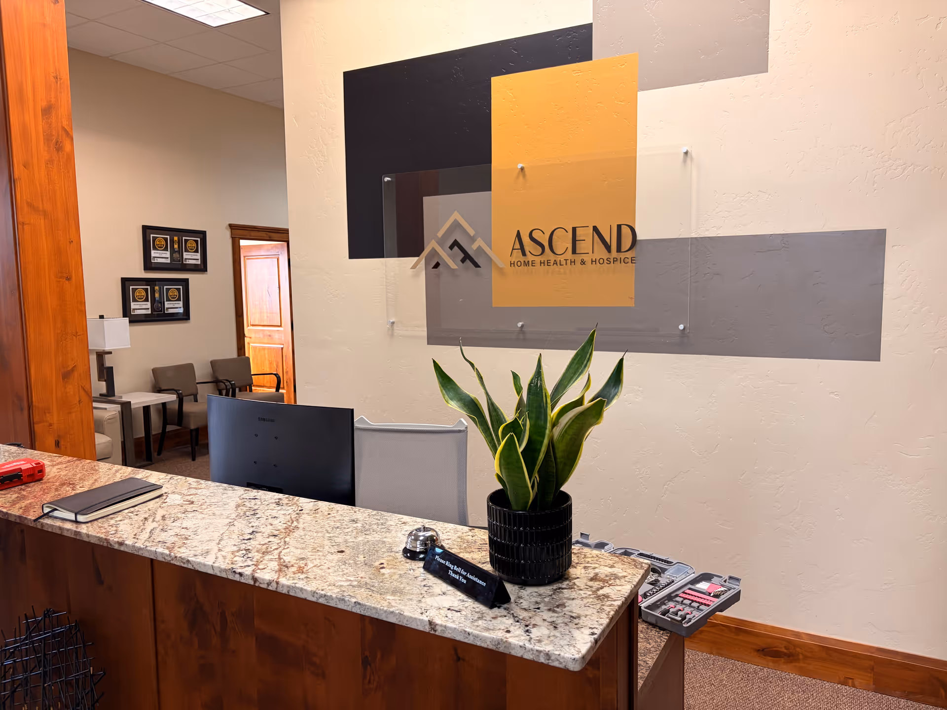 Reception desk with plant and Ascend sign in a lobby area.