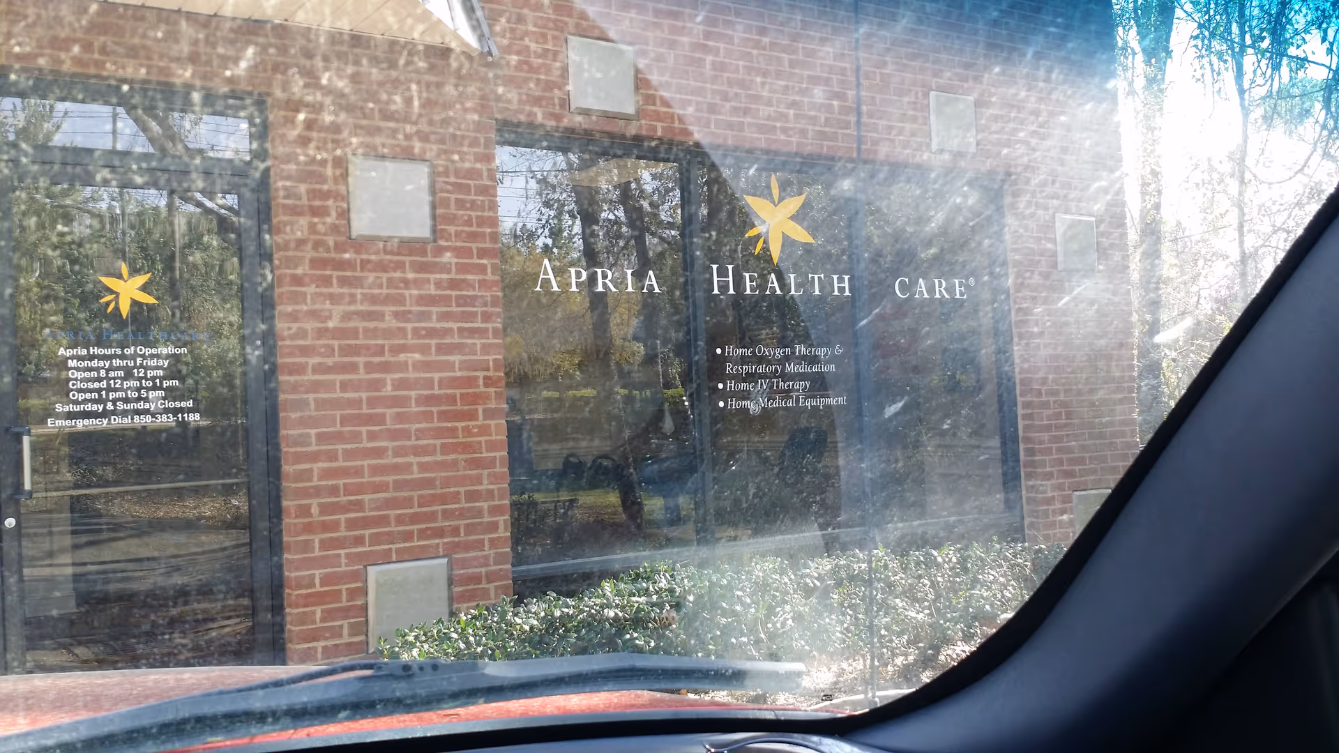 Brick building exterior with large glass windows displaying Apria Health Care signage.
