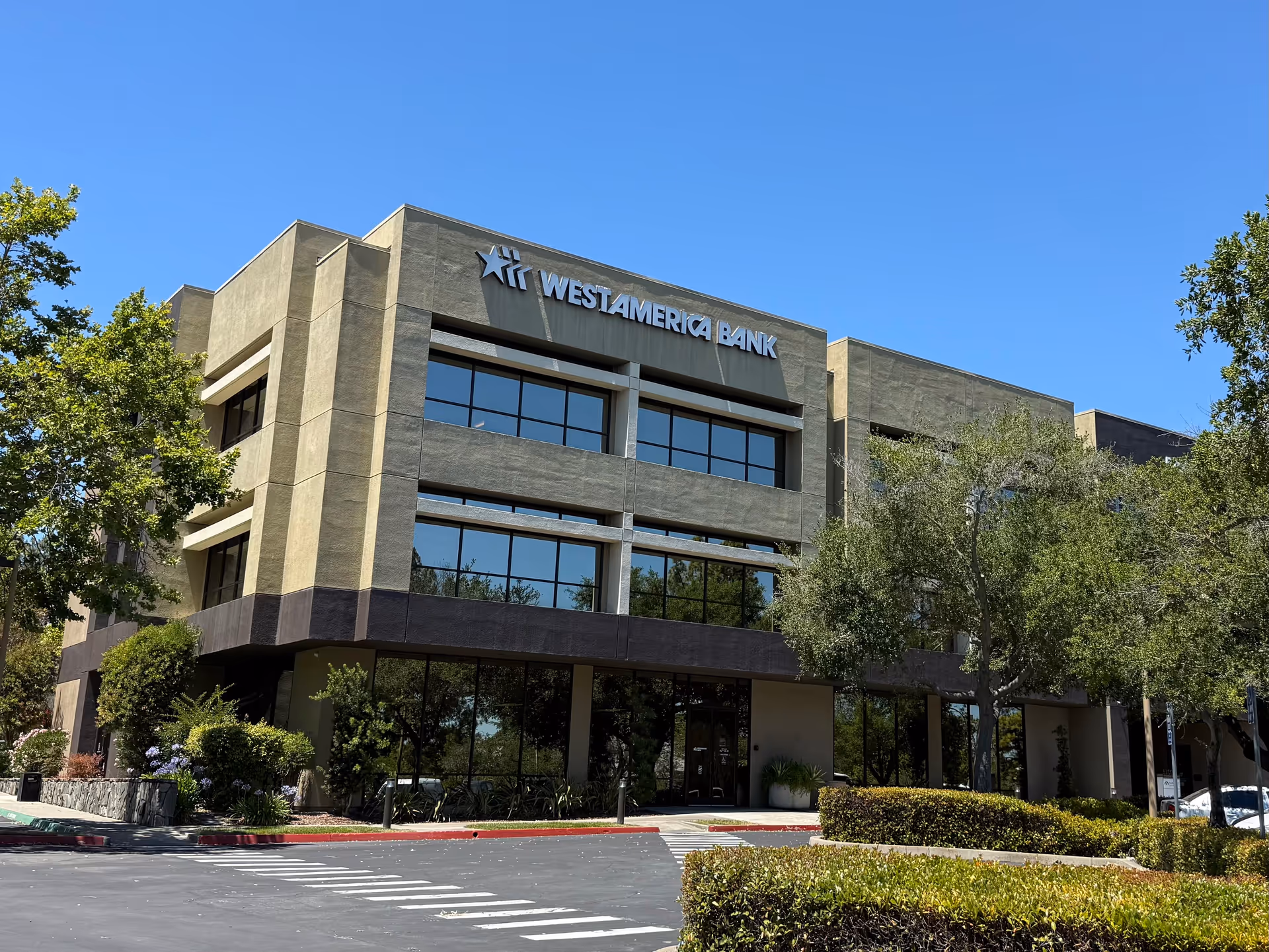Modern two-story bank building with large windows and blue sky.