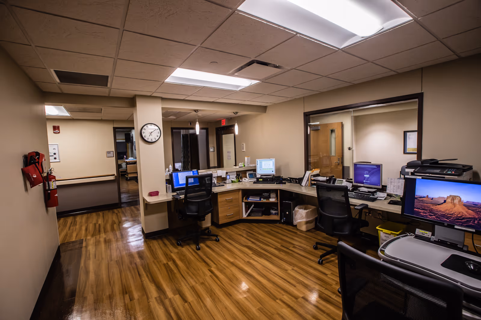 Spacious beige-walled reception area in a senior living facility with desks and computers.