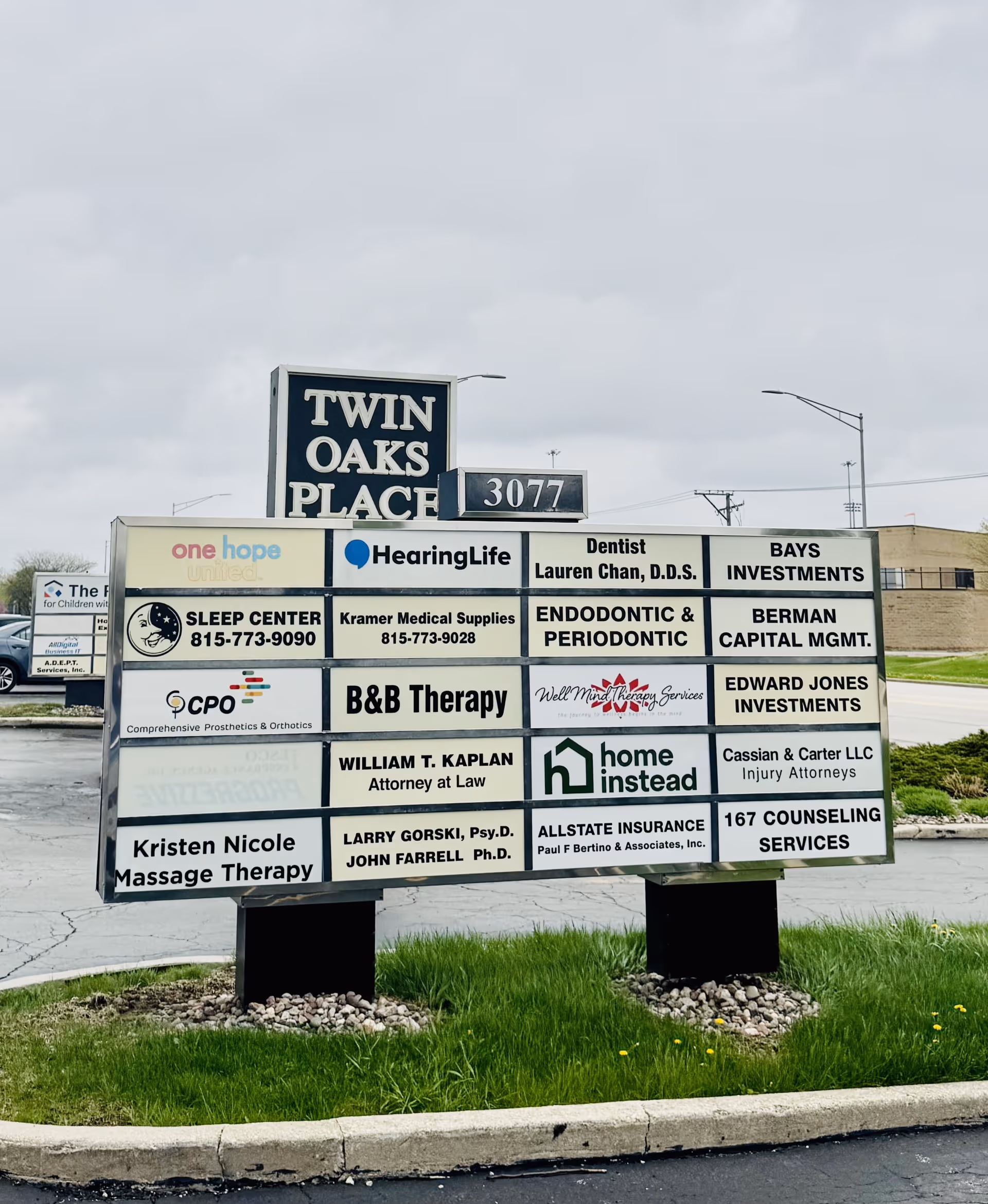 A large outdoor sign at Twin Oaks Place listing Home Instead among other tenants.