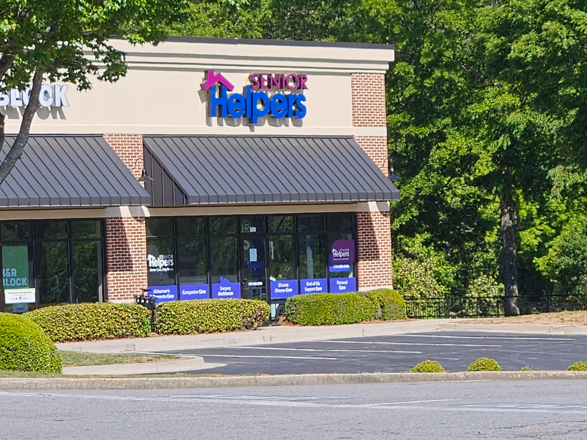 Exterior view of a Senior Helpers facility with parking lot and green landscaping.