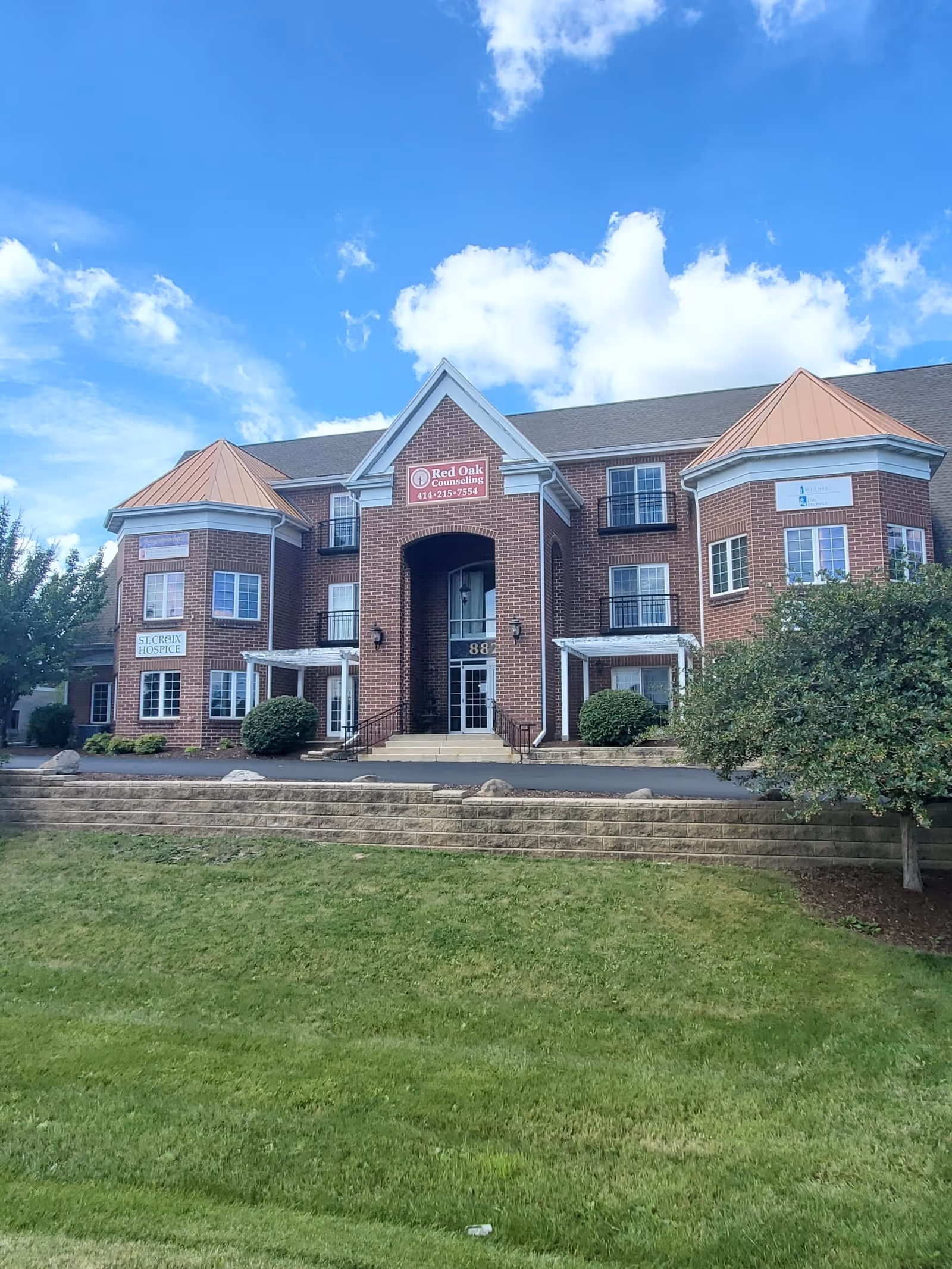 Brick senior care building front with entrance, signage, and manicured landscaping.
