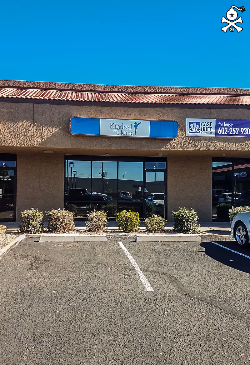 Exterior storefront of a strip mall with Kindred at Home sign and glass windows.