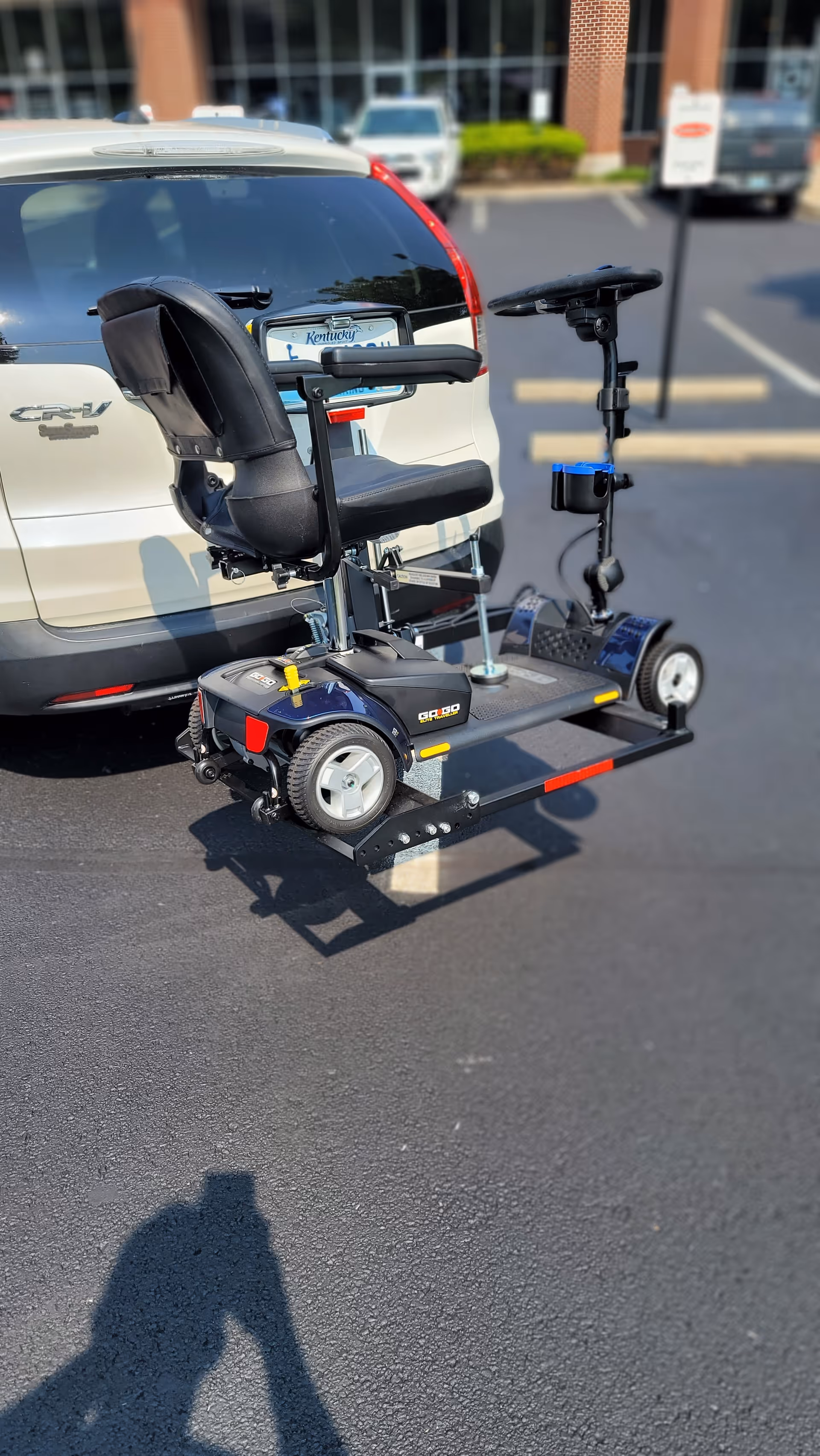A mobility scooter is parked in a parking lot beside a white SUV.