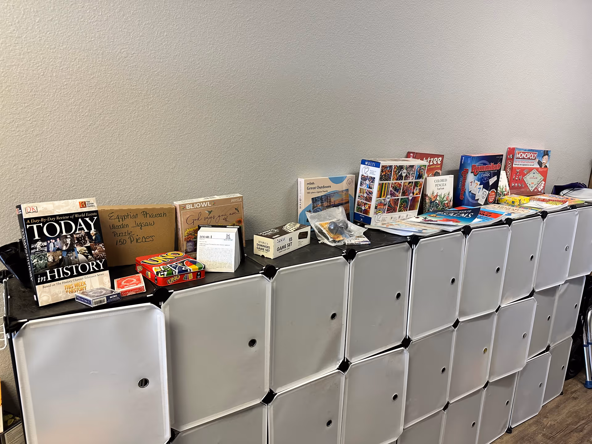Row of white cubbies topped with board games and puzzles.