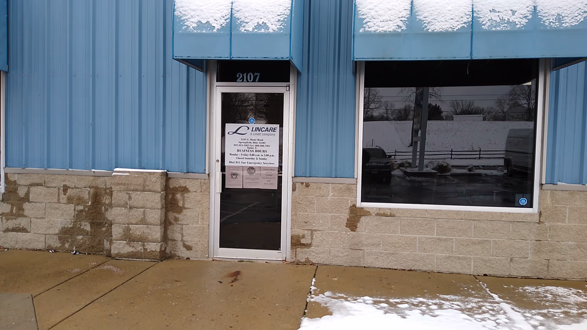 Blue metal building exterior with a glass door labeled Lincare and a large window.