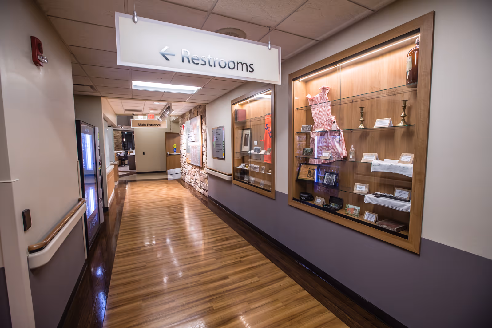 Interior corridor of a senior facility with display cases and a Restrooms sign