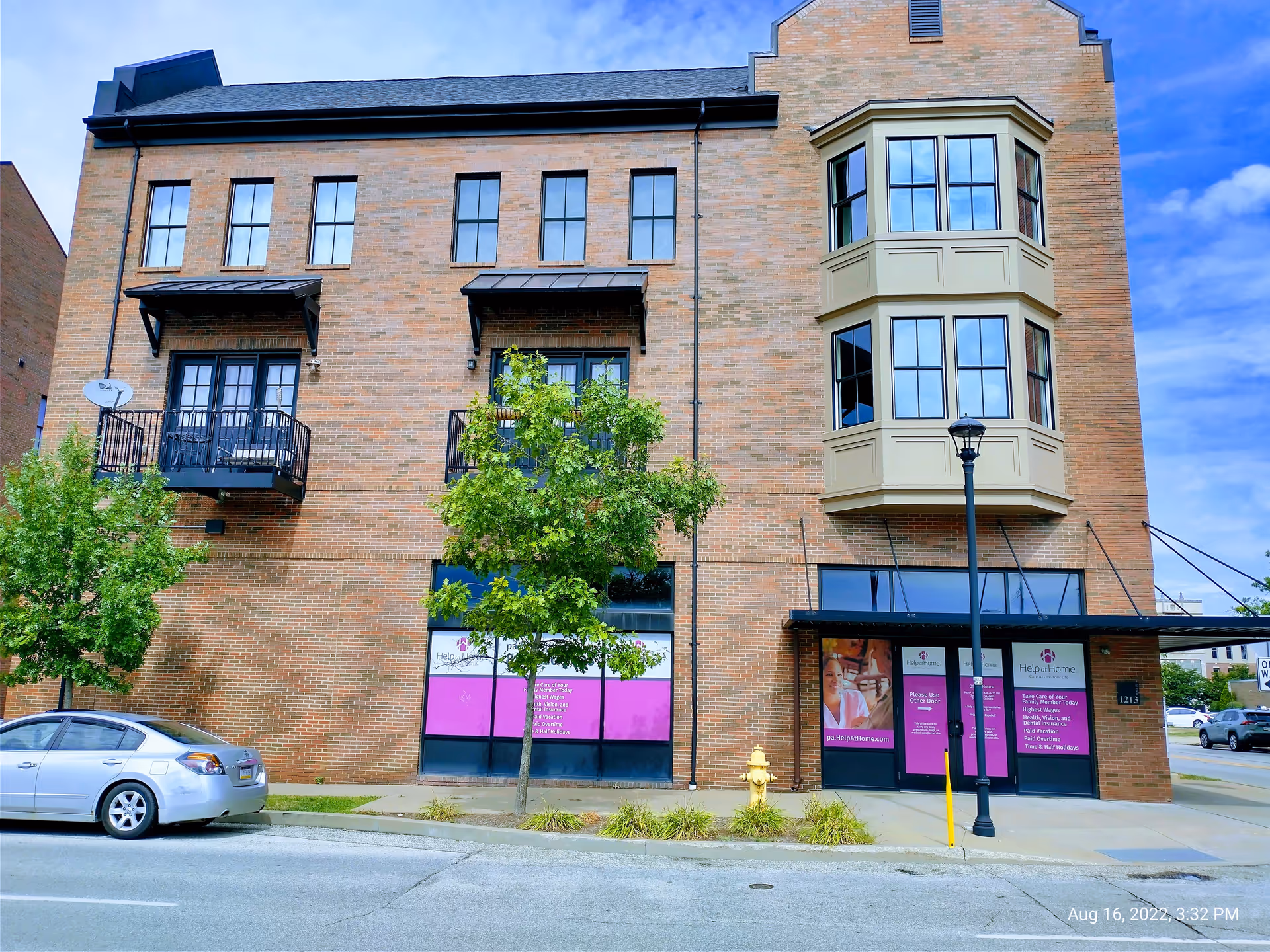 Brick multi-story senior-living building with purple storefront windows and a parked car.