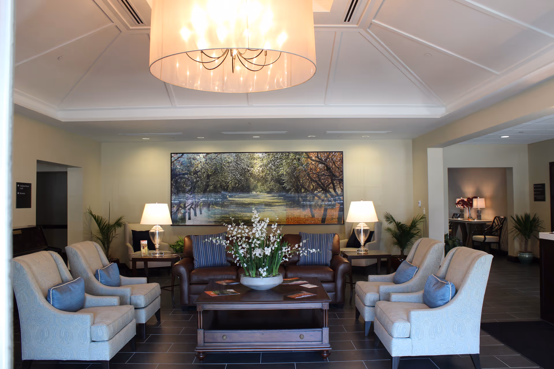 Spacious hospice lobby with beige seating, a brown leather sofa, and a large wall artwork.
