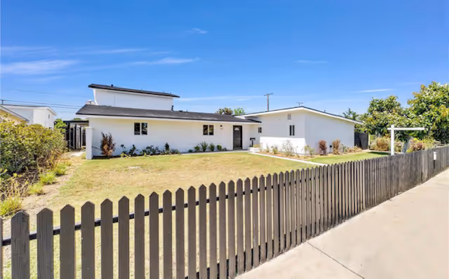 Single-story white residential facility with a wooden fence and well-kept front yard.