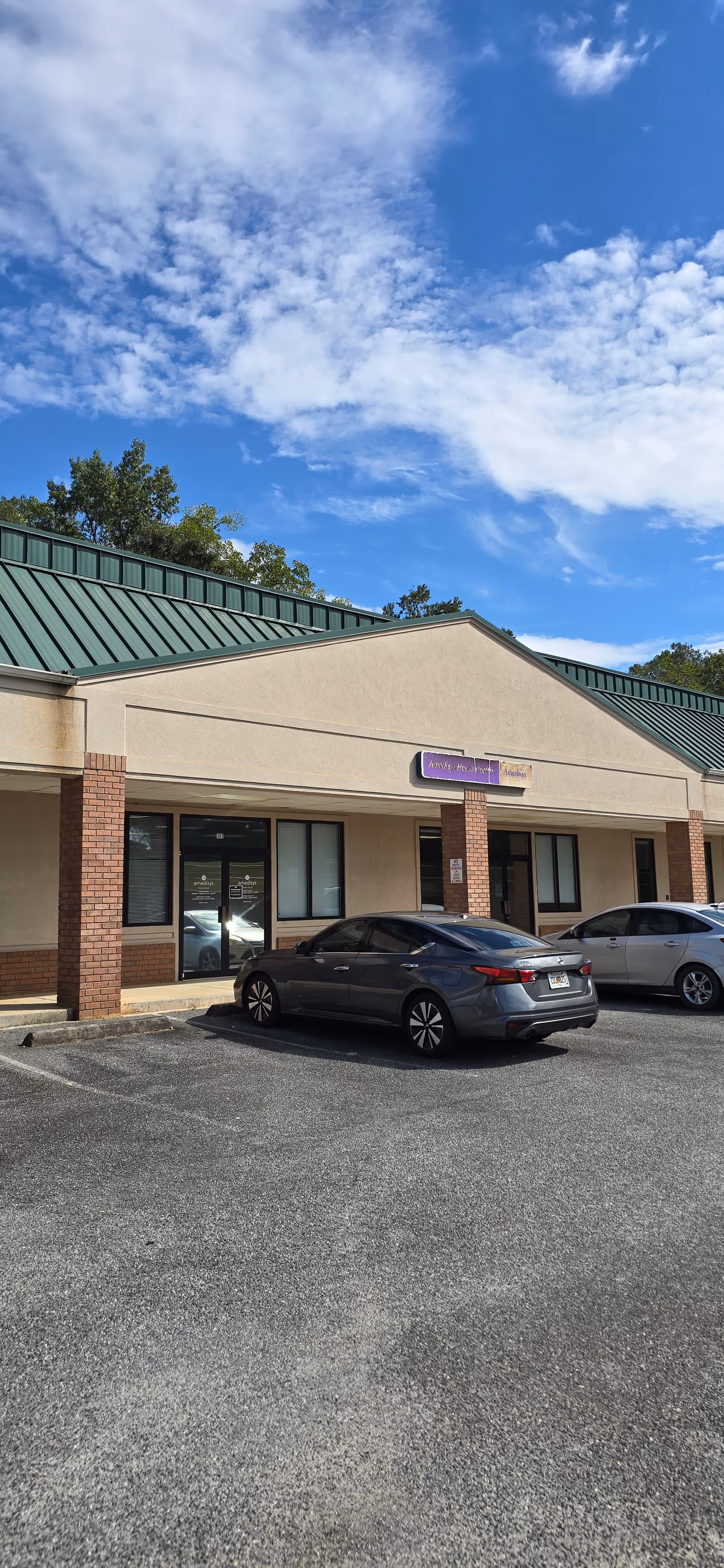 Exterior view of Amedisys Home Health Care facility with parked cars.
