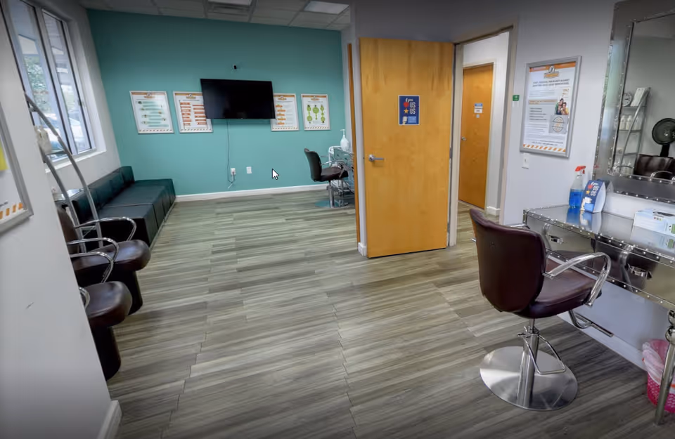Interior waiting area and salon station with teal walls, TV, chairs, and door.