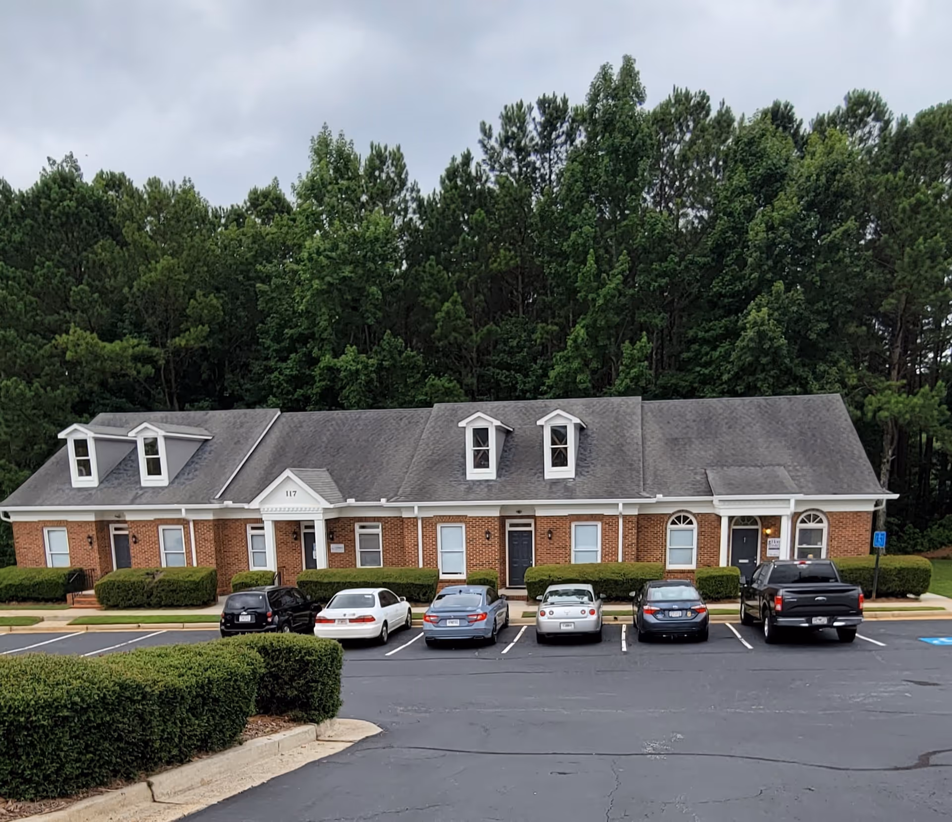 Home Instead senior living building with parked cars and green hedges in front