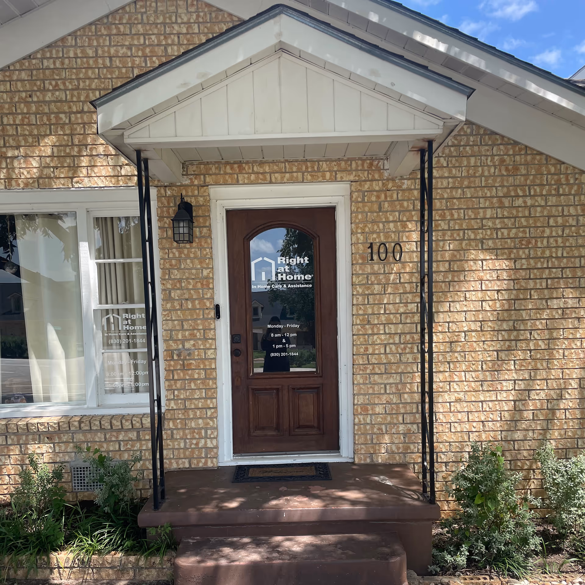 Brick building entrance with a wooden door labeled Right at Home, 100