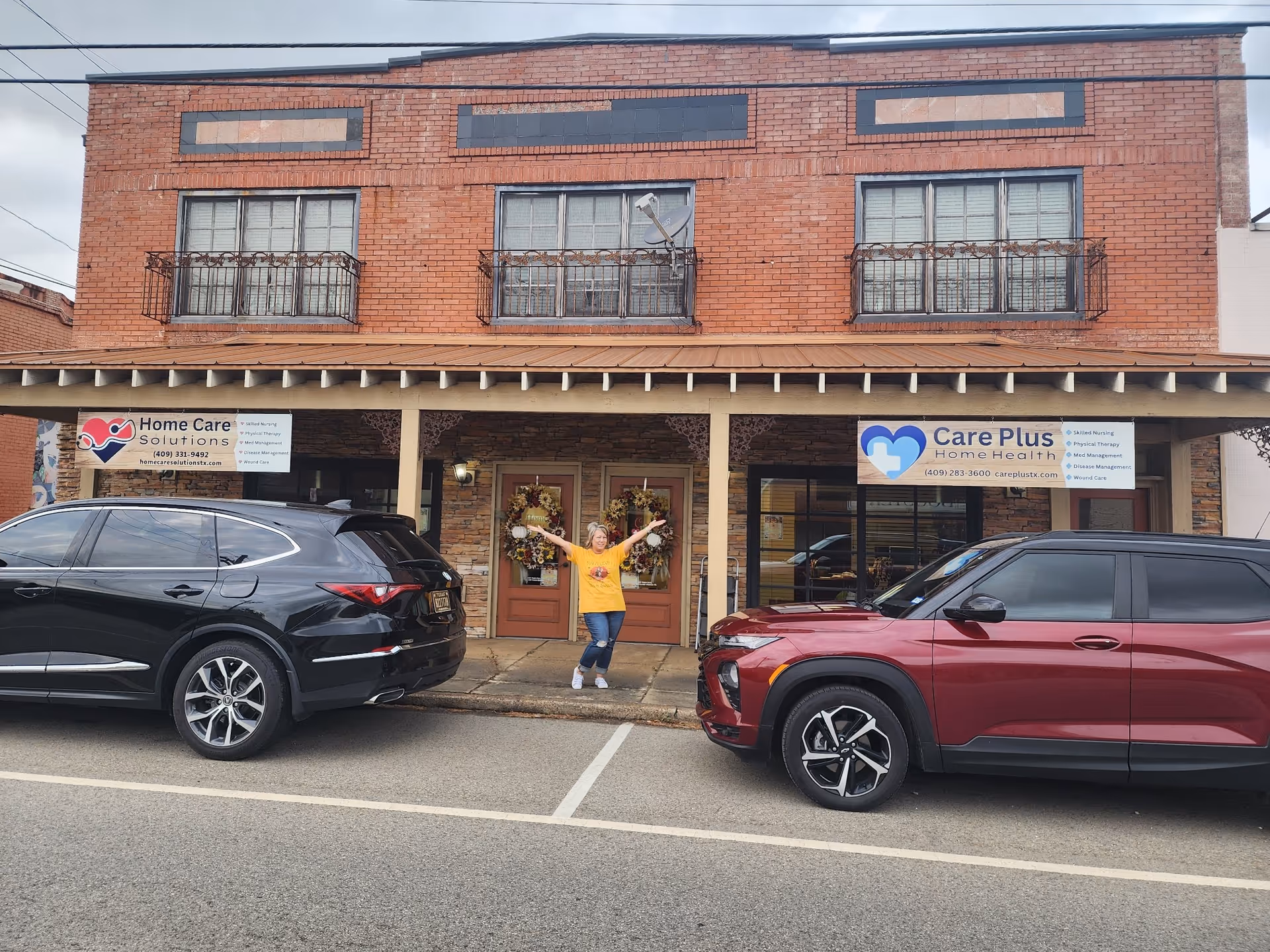Brick storefront with Care Plus Home Health signs and a person posing outside.