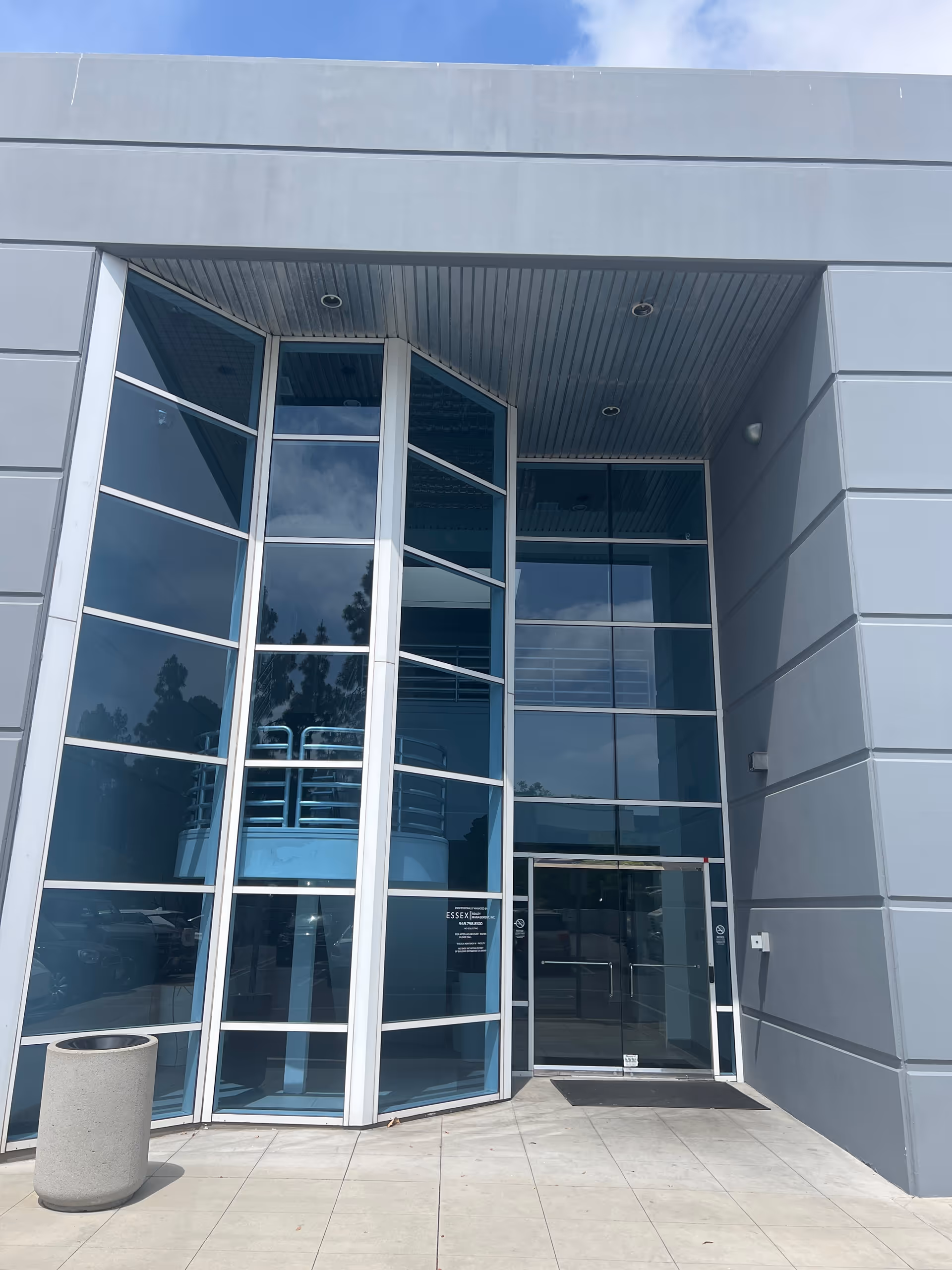 Modern gray facility entrance with tall glass windows and double doors.