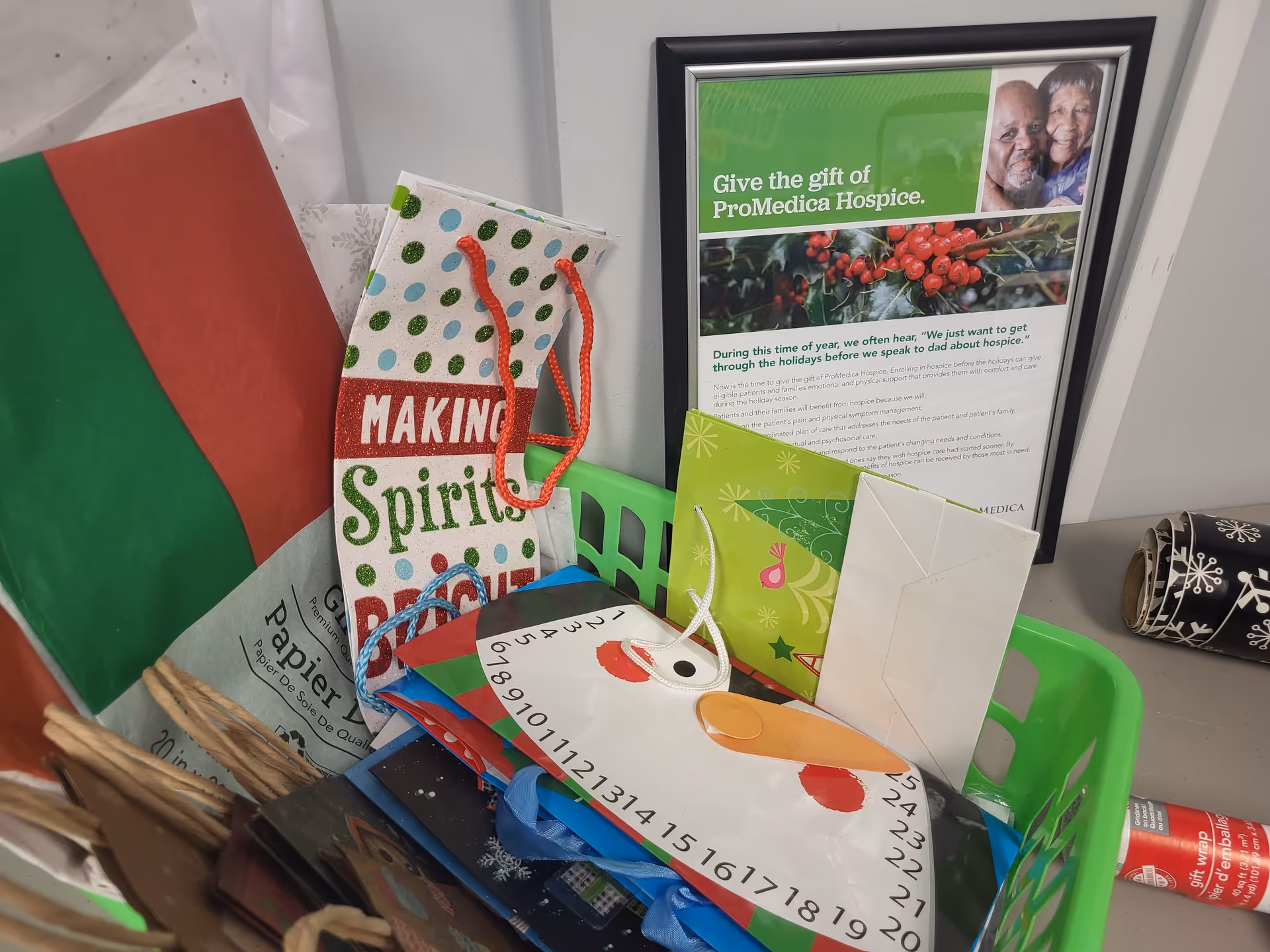 Several gift bags, cards, and a framed poster clutter a desk inside a senior care facility.