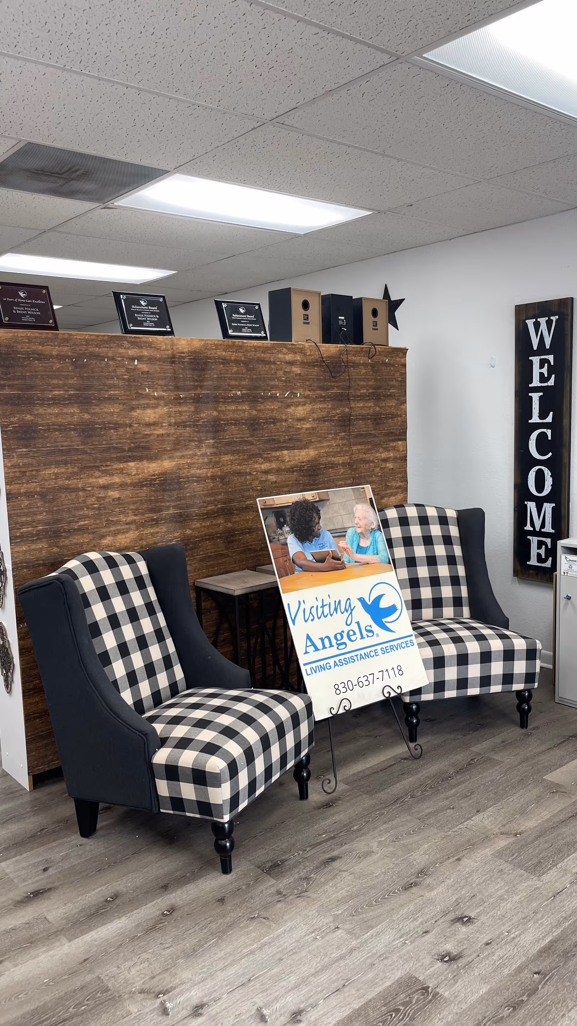 Interior waiting area with two checkered chairs, a wooden counter, and a welcome sign.