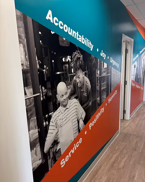 Interior hallway with teal and red banner wall showing Accountability, Joy, Urgency, and Service.
