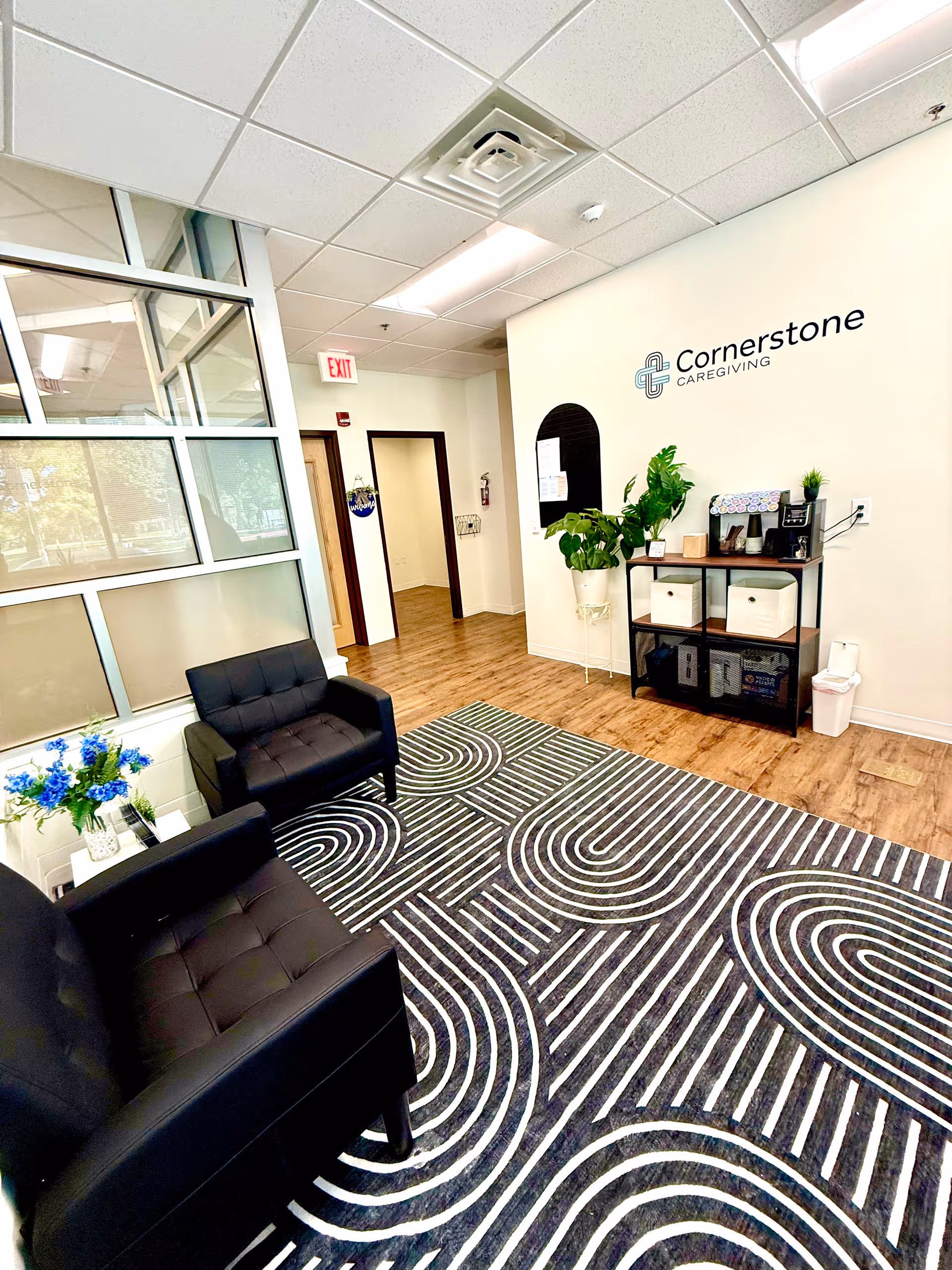 Lobby area of Cornerstone Caregiving with black seating, patterned rug, and reception shelf.