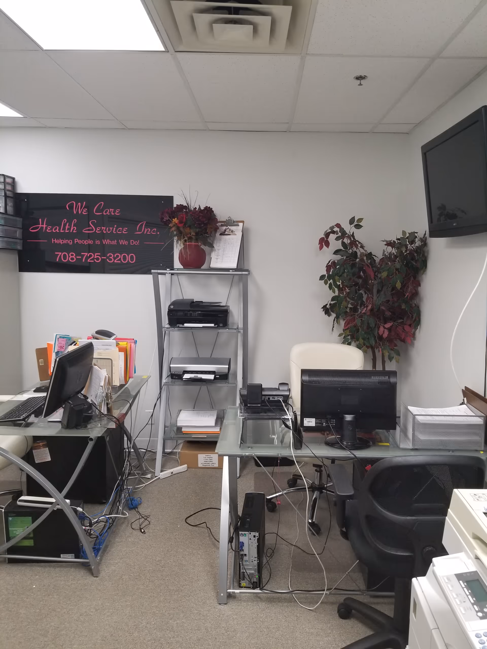 Office workspace inside a senior care facility with desks, computers, and printers.