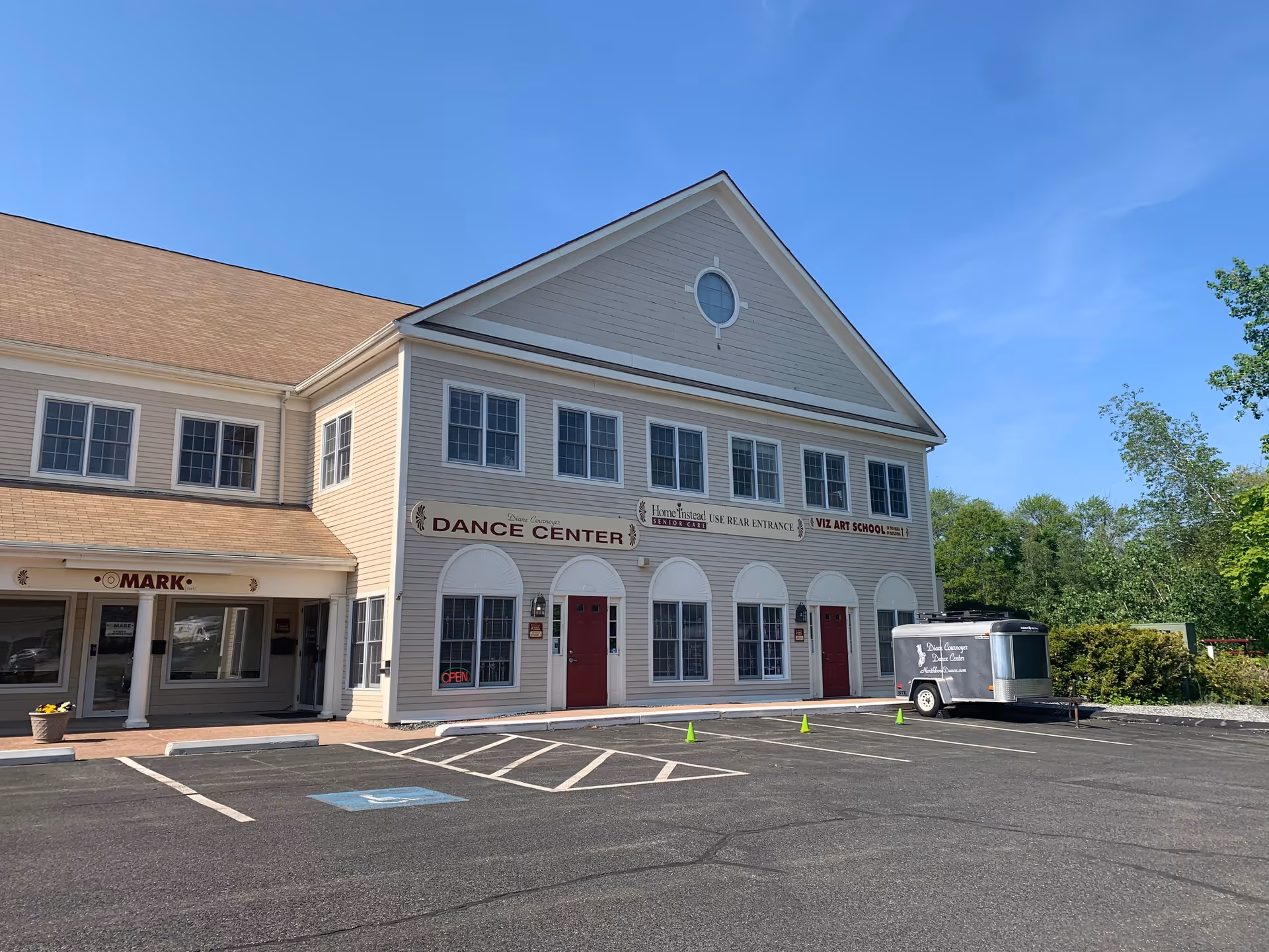 Two-story beige building with Home Instead and dance center signage in a parking lot.