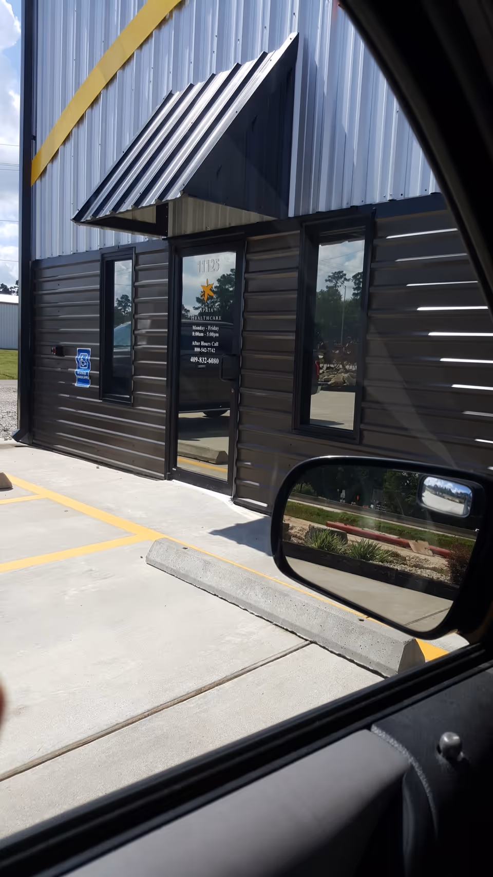 Exterior view of a dark metal Apria Healthcare building with glass door and awning.