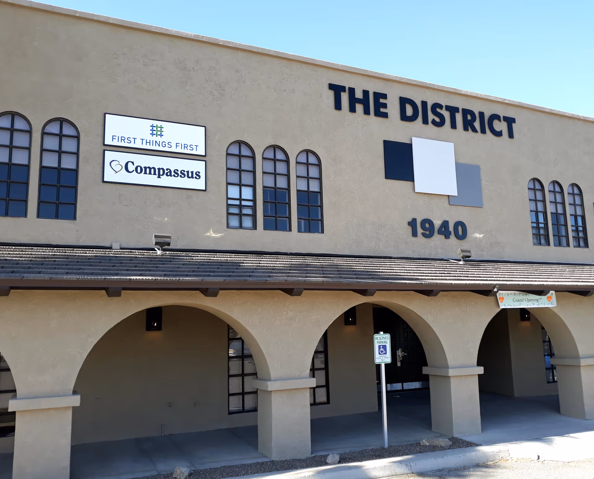 Front exterior of The District building with Compassus signs and arched entryways.