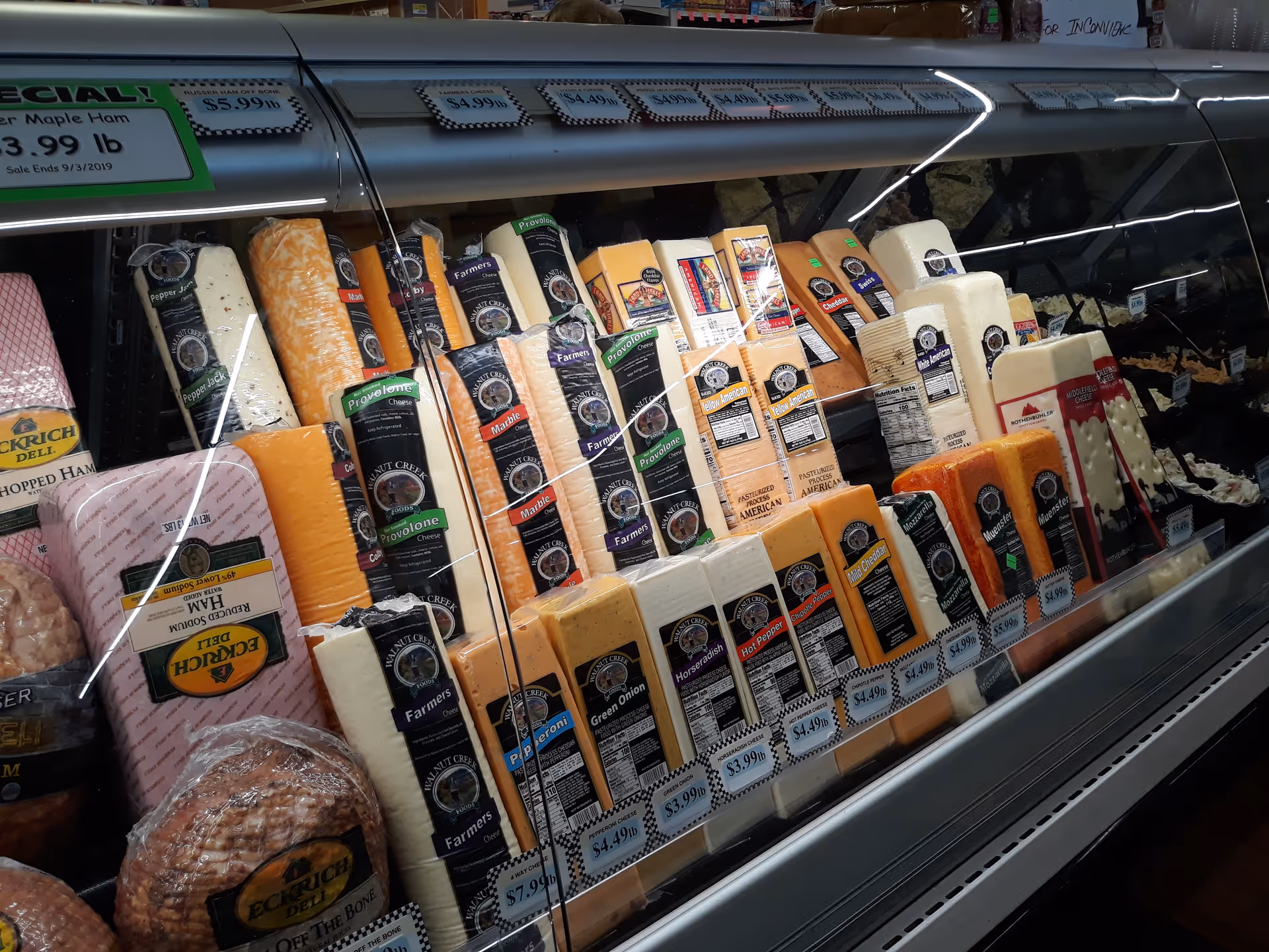 Refrigerated cheese display in Discount Drug Mart with assorted blocks and labels.