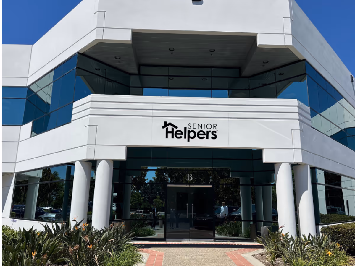 Modern white building entrance with glass walls and Senior Helpers sign.