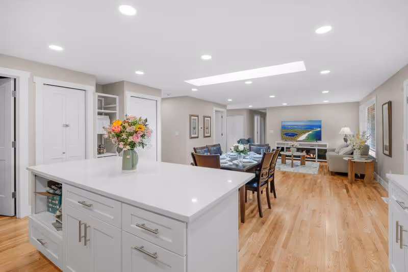 Open-concept senior living common area with white island, dining table, and living room.
