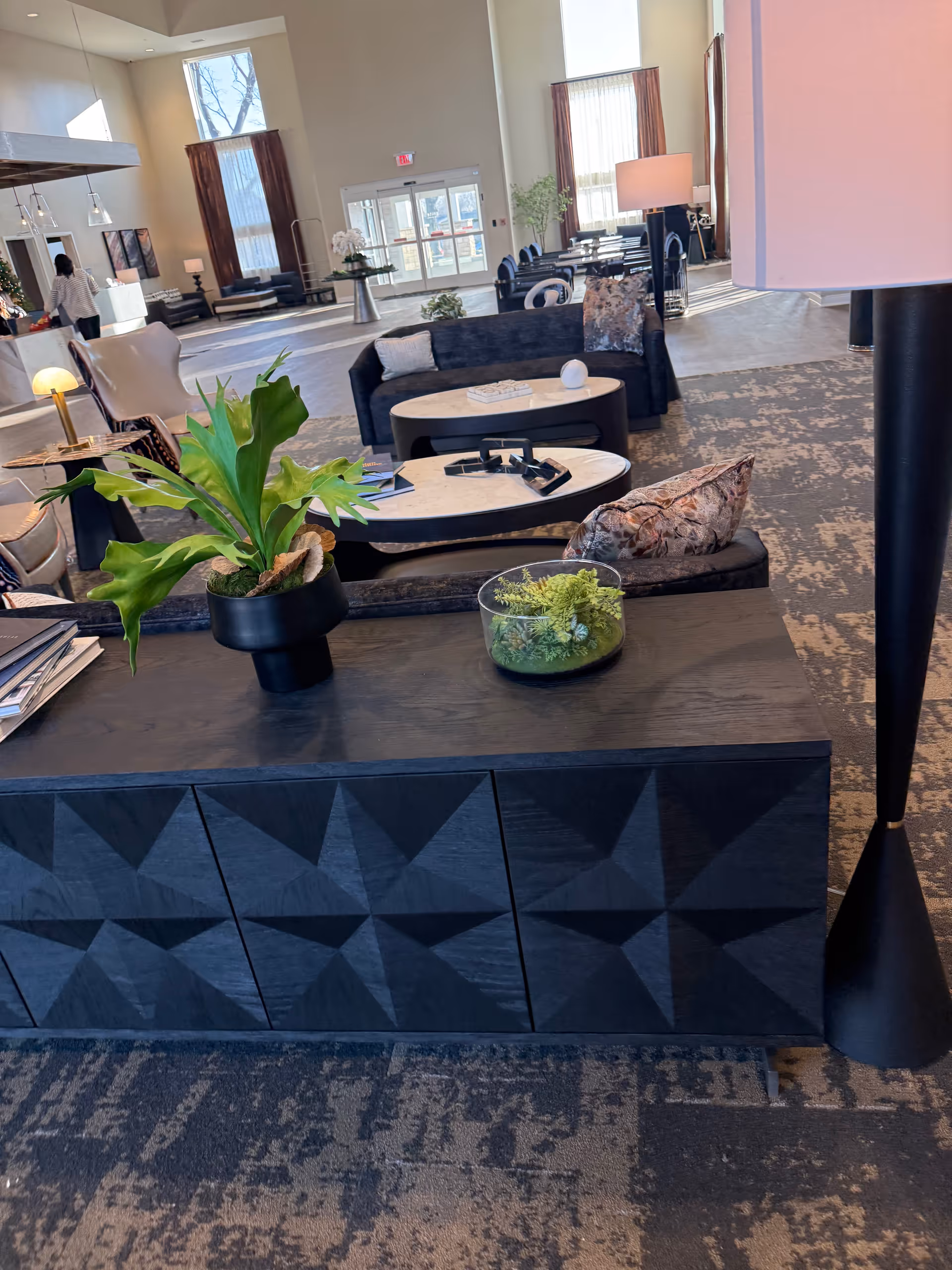 Spacious lobby lounge with seating, coffee tables, and potted plants.