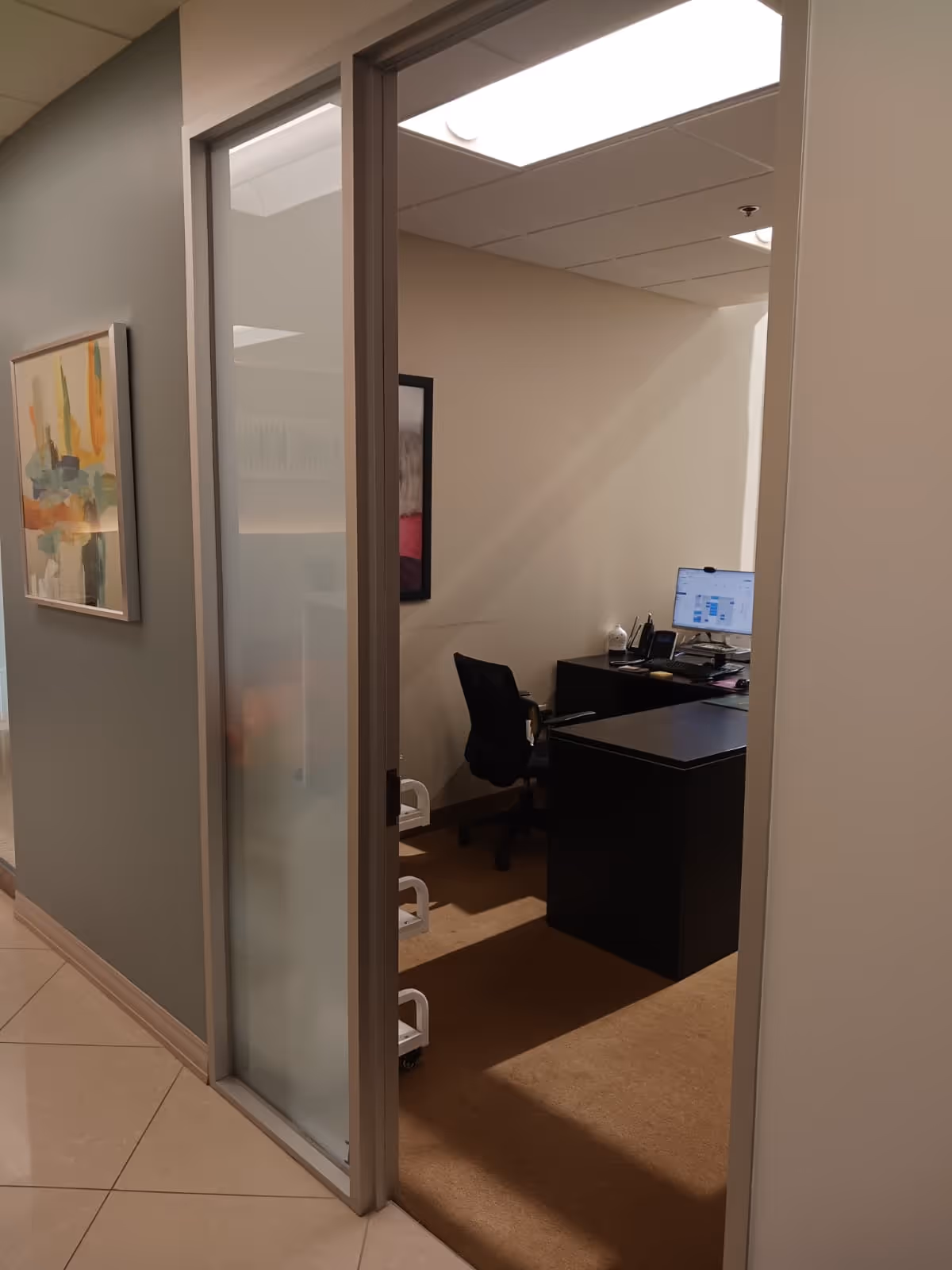 Interior office doorway opens to a desk, chair, and computer setup.